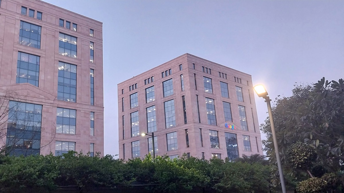 Google's India office towers in Gurugram at dusk, with the Google logo lit on the facade